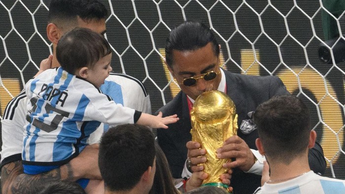 18 December 2022, Qatar, Lusail: Soccer, World Cup, Argentina - France, final round, final, Lusail Stadium, Turkish restaurateur Nusret Gökçe, alias Salt Bae, kisses the World Cup trophy. Photo: Robert Michael/dpa - IMPORTANT NOTE: In accordance with the requirements of the DFL Deutsche Fußball Liga and the DFB Deutscher Fußball-Bund, it is prohibited to use or have used photographs taken in the stadium and/or of the match in the form of sequence pictures and/or video-like photo series. (Photo by Robert Michael/picture alliance via Getty Images)