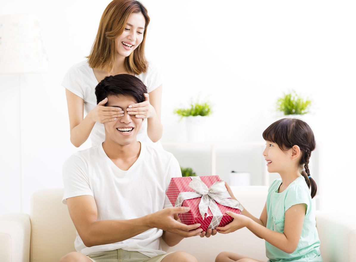 surprised Father receiving gift box from wife and daughter