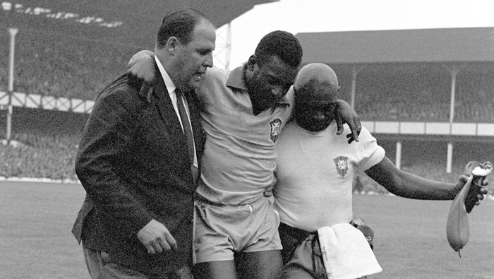 Brazils Pele (c) is helped from the pitch by team doctor Hilton Gosling (l) and trainer Americo (r)   (Photo by PA Images via Getty Images)