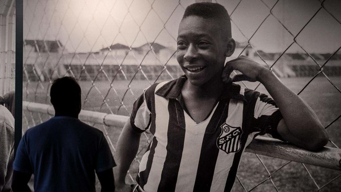 TOPSHOT - A visitor looks at a picture of Brazils football legend Edson Arantes do Nascimento Pele, exhibited at the Pele Museum, in Santos, Brazil, on December 27, 2022. - Family members spent Christmas on Sunday with Pele at the Sao Paulo hospital where the legendary footballer is battling worsening cancer as well as kidney and heart problems, according to social media posts by his children. Fans of the player, considered by many the greatest of all time, have been expressing hope for his recovery since he was hospitalized in late November. (Photo by NELSON ALMEIDA / AFP) (Photo by NELSON ALMEIDA/AFP via Getty Images)