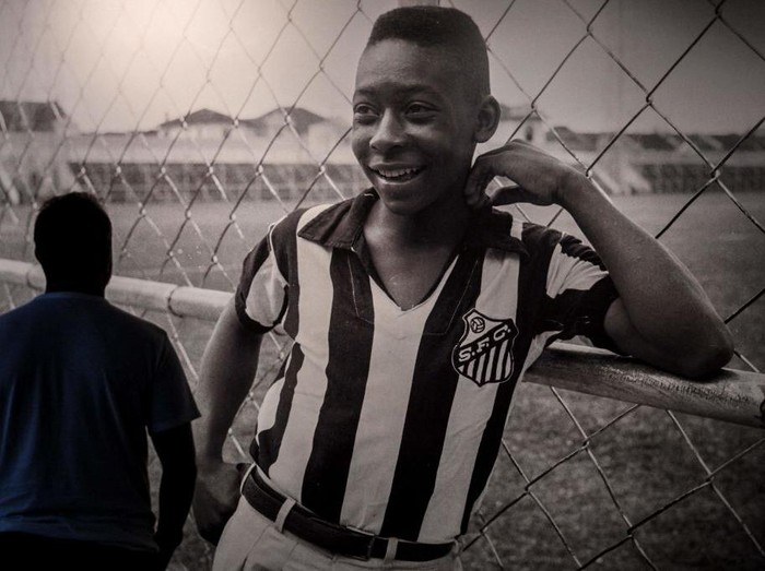 TOPSHOT - A visitor looks at a picture of Brazil's football legend Edson Arantes do Nascimento 'Pele', exhibited at the Pele Museum, in Santos, Brazil, on December 27, 2022. - Family members spent Christmas on Sunday with Pele at the Sao Paulo hospital where the legendary footballer is battling worsening cancer as well as kidney and heart problems, according to social media posts by his children. Fans of the player, considered by many the greatest of all time, have been expressing hope for his recovery since he was hospitalized in late November. (Photo by NELSON ALMEIDA / AFP) (Photo by NELSON ALMEIDA/AFP via Getty Images)
