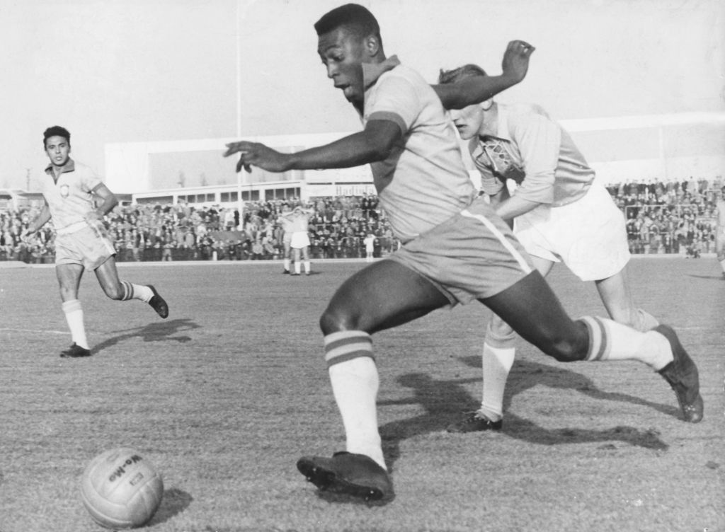 Brazilian striker Pele (front) runs with the ball past a Swedish defender of the Malmoe FF soccer club during an international friendly between Malmoe FF and the Brazilian national team in Malmoe, Sweden, 8 May 1960. Brazil won 7-1. Pele became famous when he played with the Brazilian national team at the 1958 FIFA World Cup in Sweden and won the first World Champion title for Brazil. (Photo by/picture alliance via Getty Images)