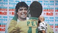 Seseorang berjalan melewati kolase di dinding yang menggambarkan Pele dan Maradona di Sao Paulo, Brasil, 29 Desember 2022. REUTERS/Carla Carniel.