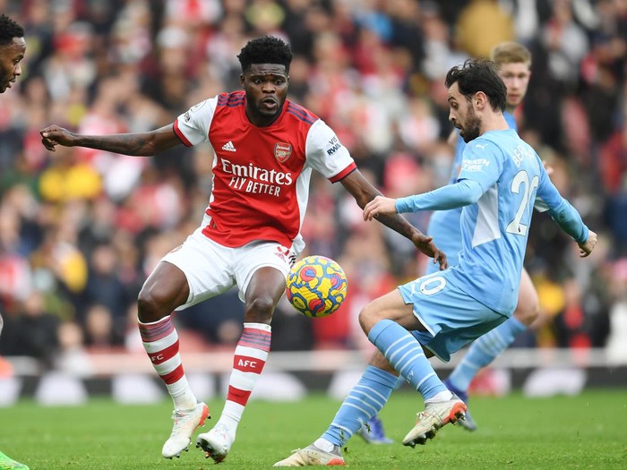 LONDON, ENGLAND - JANUARY 01: Thomas Partey of Arsenal challenges Bernardo Silva of Man City during the Premier League match between Arsenal  and  Manchester City at Emirates Stadium on January 01, 2022 in London, England. (Photo by Stuart MacFarlane/Arsenal FC via Getty Images)