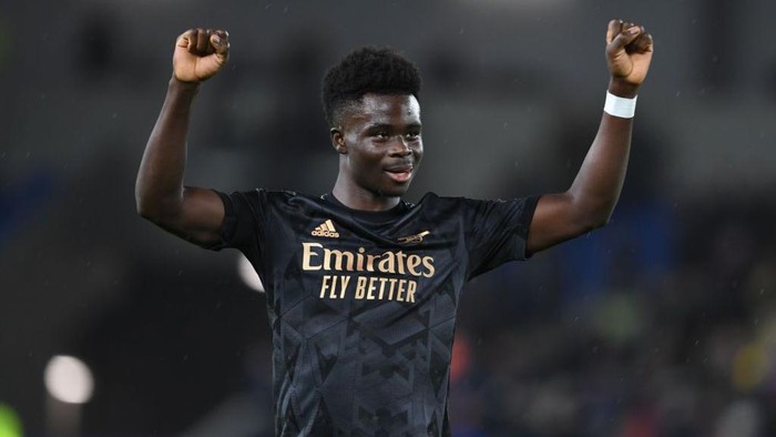 BRIGHTON, ENGLAND - DECEMBER 31: Bukayo Saka celebrates with the Arsenal fans after the Premier League match between Brighton & Hove Albion and Arsenal FC at American Express Community Stadium on December 31, 2022 in Brighton, England. (Photo by Stuart MacFarlane/Arsenal FC via Getty Images)