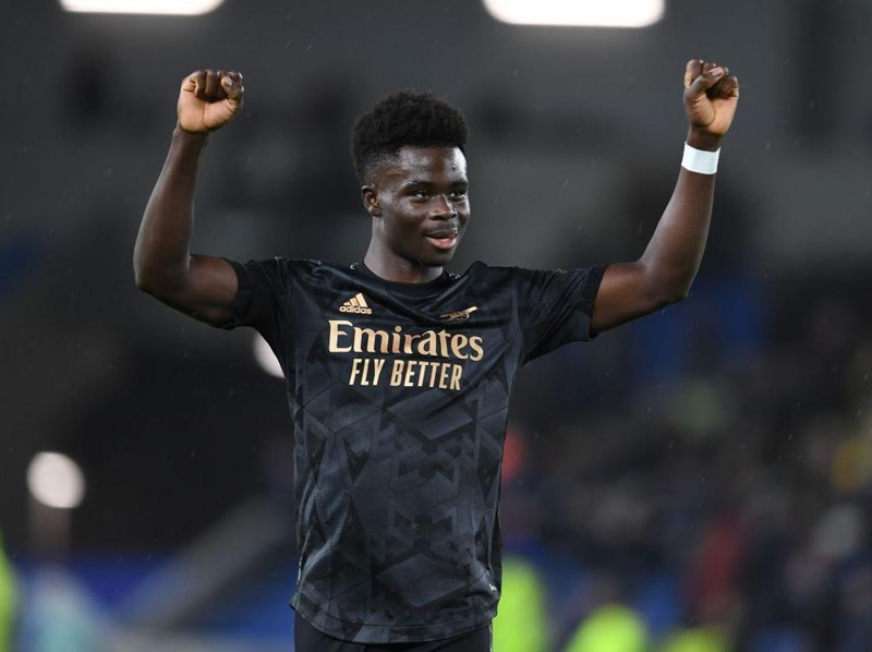 BRIGHTON, ENGLAND - DECEMBER 31: Bukayo Saka celebrates with the Arsenal fans after the Premier League match between Brighton & Hove Albion and Arsenal FC at American Express Community Stadium on December 31, 2022 in Brighton, England. (Photo by Stuart MacFarlane/Arsenal FC via Getty Images)