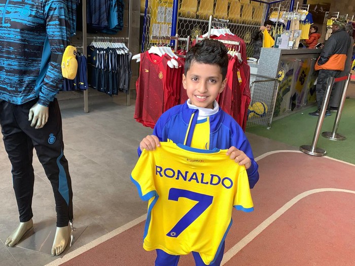 A young fan holds t-shirt bearing the name Ronaldo and number 7, at the Saudi Al Nassr FC shop in the Saudi capital Riyadh, on December 31, 2022. - Cristiano Ronaldo on December 30 signed for Al Nassr of Saudi Arabia, the club announced, in a deal believed to be worth more than 200 million euros. The 37-year-old penned a contract which will take him to June 2025. (Photo by Fayez Nureldine / AFP) (Photo by FAYEZ NURELDINE/AFP via Getty Images)