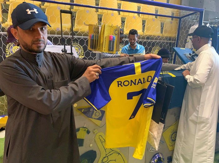 A fan holds t-shirt bearing the name Ronaldo and number 7, at the Saudi Al Nassr FC shop in the Saudi capital Riyadh, on December 31, 2022. - Cristiano Ronaldo on December 30 signed for Al Nassr of Saudi Arabia, the club announced, in a deal believed to be worth more than 200 million euros. The 37-year-old penned a contract which will take him to June 2025. (Photo by Fayez Nureldine / AFP) (Photo by FAYEZ NURELDINE/AFP via Getty Images)
