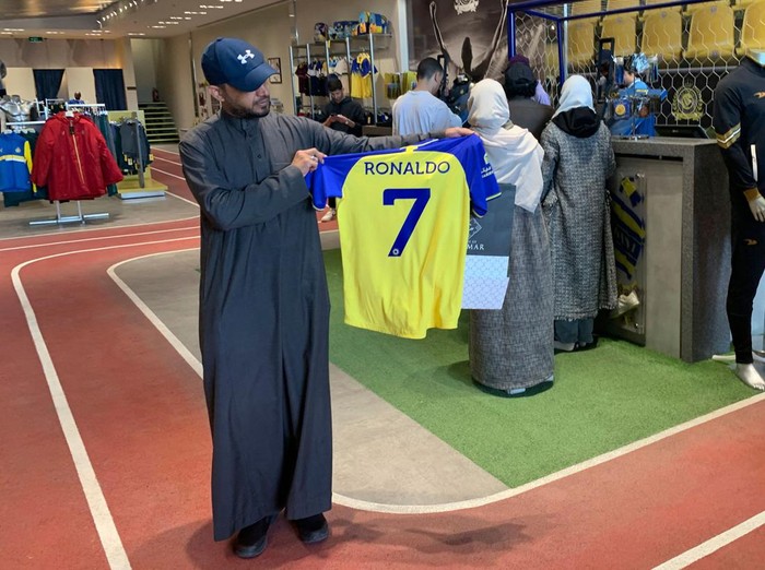 A fan holds t-shirt bearing the name Ronaldo and number 7, at the Saudi Al Nassr FC shop in the Saudi capital Riyadh, on December 31, 2022. - Cristiano Ronaldo on December 30 signed for Al Nassr of Saudi Arabia, the club announced, in a deal believed to be worth more than 200 million euros. The 37-year-old penned a contract which will take him to June 2025. (Photo by Fayez Nureldine / AFP) (Photo by FAYEZ NURELDINE/AFP via Getty Images)
