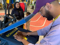 Para fans juga dipersilakan membawa jersey resmi Al Nassr mereka untuk dicetak nama dan nomor punggung Ronaldo. Hal ini dilakukan lantaran stok jersey CR7 ludes terjual! (Foto: AFP via Getty Images/FAYEZ NURELDINE)