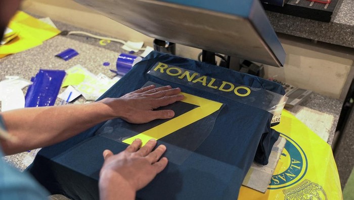 A staff member heat presses an Al Nassr soccer jersey with Cristiano Ronaldos surname on the back, in Riyadh, Saudi Arabia December 31, 2022. REUTERS/Mohammed Benmansour