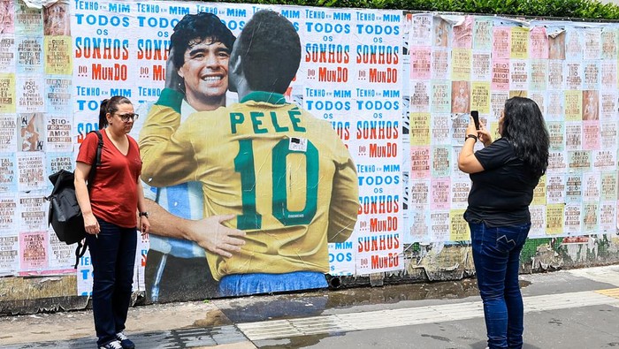 SAO PAULO, BRAZIL - DECEMBER 30: A view of an image in Sao Paulo shows Pele hugs Maradona, as people take photos in Brazil, on December 30, 2022. Brazilian football legend, 3-time World Cup winner Pele lost his fight to colon cancer and passed away at the age 82 on Dec. 29, 2022. (Photo by Marcello Zambrana/Anadolu Agency via Getty Images)