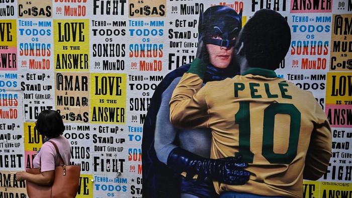 View of a street poster art by Luis Bueno, known as BuenoCaos, depicting Brazilian football legend Pele hugging Batman in Sao Paulo, Brazil, on December 26, 2022. - Family members spent Christmas on Sunday with Pele at the Sao Paulo hospital where the legendary footballer is battling worsening cancer as well as kidney and heart problems, according to social media posts by his children. Fans of the player, considered by many the greatest of all time, have been expressing hope for his recovery since he was hospitalized in late November. (Photo by NELSON ALMEIDA / AFP) (Photo by NELSON ALMEIDA/AFP via Getty Images)