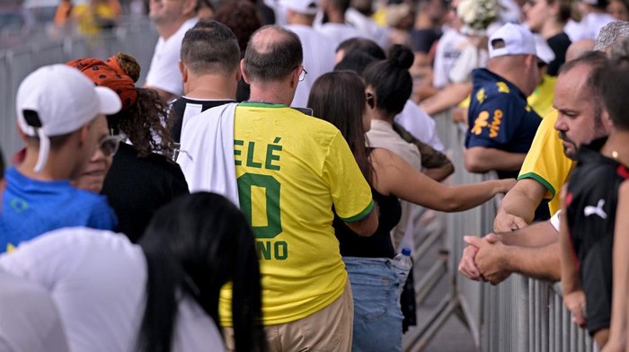 SANTOS, BRAZIL - JANUARY 02: Fans queue outside the Urbano Caldeira Stadium ahead of football legend Peles funeral, which begins later this morning at the stadium on January 02, 2023 in Santos, Brazil. Brazilian football icon Edson Arantes do Nascimento, better known as Pele, died on December 29, 2022 aged 82 after a battle with cancer in Sao Paulo, Brazil. The three-time World Cup champion with Brazil is considered one of the greatest football legends of all time. (Photo by Pedro Vilela/Getty Images)