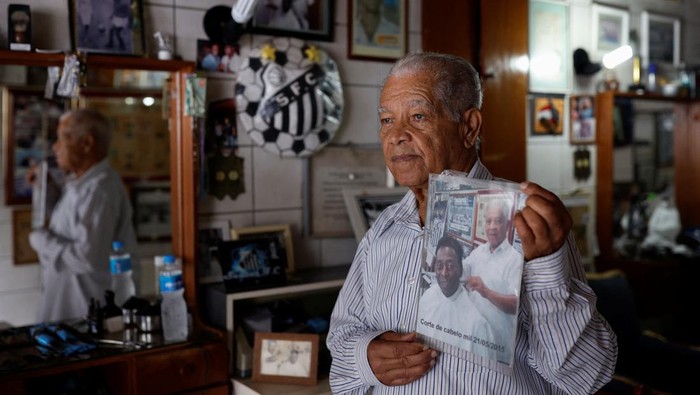 Sosok Didi Si Tukang Cukur Rambut Pele Joao Araujo, know as Didi, 84, who was hairdresser to Brazilian soccer legend Pele, holds a picture of himself with Pele, as he mourns his death, in Santos, Brazil, December 30, 2022. REUTERS/Amanda Perobelli