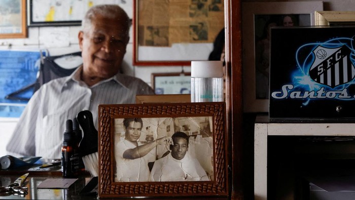 Sosok Didi Si Tukang Cukur Rambut Pele Joao Araujo, know as Didi, 84, who was hairdresser to Brazilian soccer legend Pele, holds a picture of himself with Pele, as he mourns his death, in Santos, Brazil, December 30, 2022. REUTERS/Amanda Perobelli