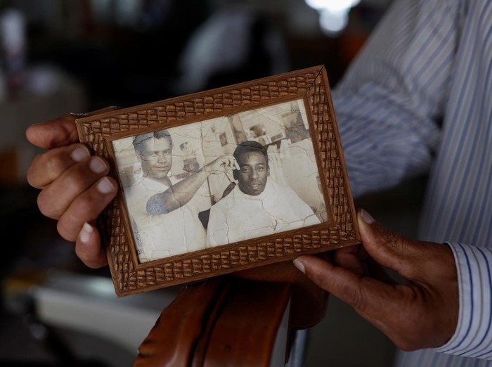 Joao Araujo, know as Didi, 84, who was hairdresser to Brazilian soccer legend Pele, holds a picture of himself with Pele, as he mourns his death, in Santos, Brazil, December 30, 2022. REUTERS/Amanda Perobelli