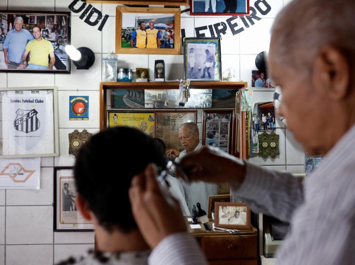 Joao Araujo, know as Didi, 84, who was hairdresser to Brazilian soccer legend Pele, holds a picture of himself with Pele, as he mourns his death, in Santos, Brazil, December 30, 2022. REUTERS/Amanda Perobelli