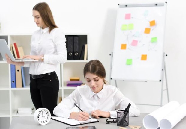 Dua perempuan mengerjakan pekerjaan kantor