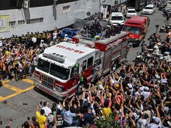 Para penggemar menyemut di pinggir jalanan yang dilalui arak-arakan jenazah Pele di Santos, Sao Paulo, Brasil, Selasa (3/1/2023). Jenazah Pele yang ditutupi bendera Brasil dan Santos FC diangkut menggunakan truk pemadam kebakaran. Nelson Almeida/AFP/Getty Images
