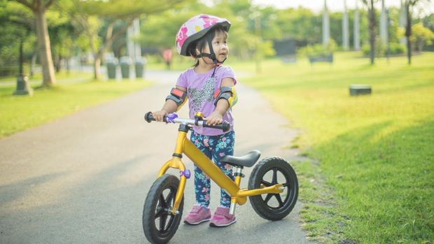 Little girl learns to riding balance bike in the park