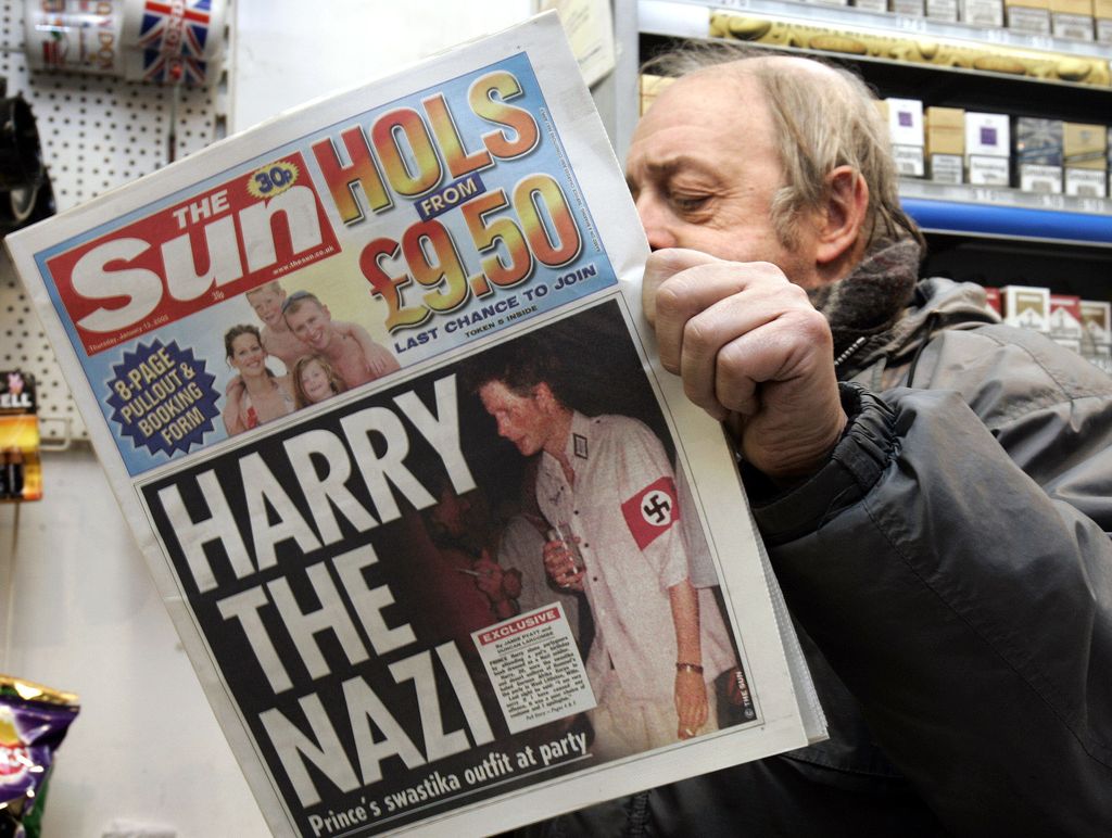 News agent Roy Ottoway reads a copy of tabloid 'The Sun', whose front page shows a picture of Britain's Prince Harry wearing a Nazi soldier's uniform to a fancy dress party, early Thursday morning, Jan. 13, 2005 at King's Cross station in London. The grandson of Queen Elizabeth II apologized Wednesday night after 'The Sun' printed the picture. Prince Harry, the second son of Prince Charles and the late Princess Diana, was shown in early editions of Thursday's issue of 