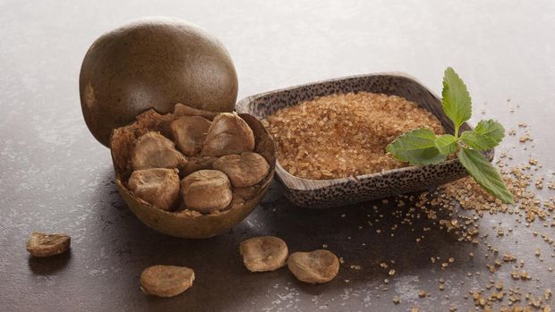 Luo Han Guo aka Monk fruit natural herbal remedy and sugar on brown background. Powerful healthy sweetener.