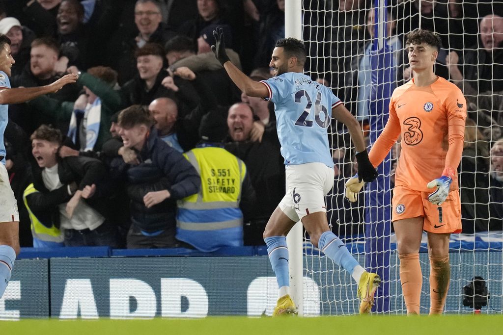 Manchester City's Riyad Mahrez celebrates after scoring the opening goal past Chelsea's goalkeeper Kepa Arrizabalaga, right, during the English Premier League soccer match between Chelsea and Manchester City at Stamford Bridge stadium in London Thursday, Jan. 5, 2023. (AP Photo/Kirsty Wigglesworth)