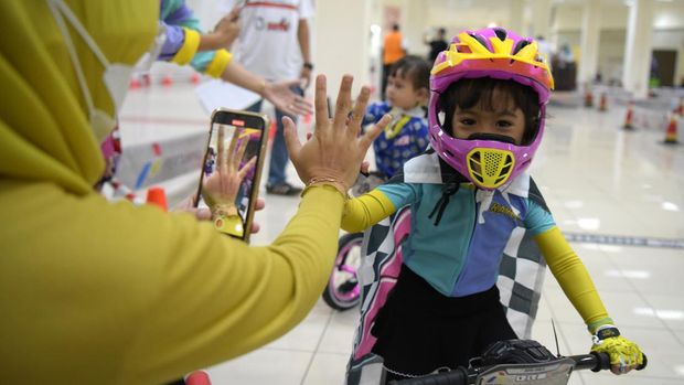 Seorang pembalap cilik melakukan tos dengan para penonton saat melaksanakan putaran kemenangan (victory lap) usai perlombaan Journalist MTB Push Bike Race 2022 di Grand ITC Permata Hijau Jakarta.