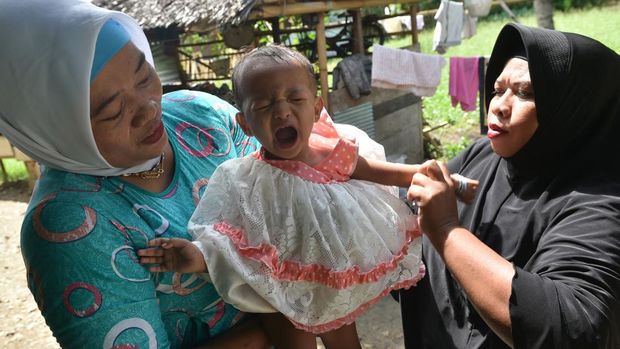 In this photograph taken on February 20, 2017, toddler Salsa Djafar (C) cries after a traditional healer conducted a circumcision in Gorontalo, in Indonesia's Gorontalo province. - Female circumcision -- also known as female genital mutilation or FGM -- has been practised for generations across Indonesia, which is the world's biggest Muslim-majority country, and is considered a rite of passage by many. (Photo by BAY ISMOYO / AFP) / TO GO WITH Indonesia-religion-rights-women,FEATURE by Olivia Rondonuwu