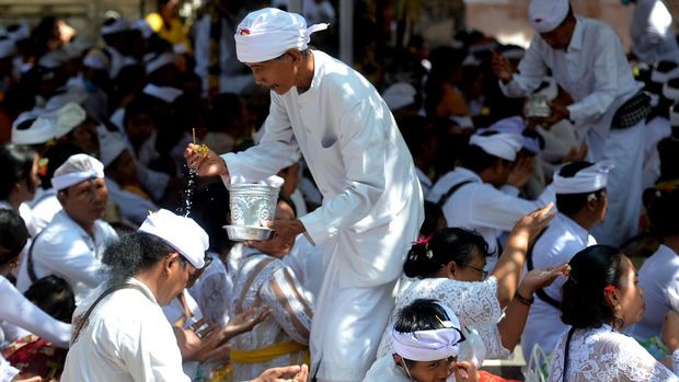 Pemuka agama Hindu memercikkan air suci saat persembahyangan bersama Hari Raya Kuningan di Pura Sakenan, Denpasar, Bali, Sabtu (14/1/2023). Hari Raya Kuningan merupakan rangkaian dari Hari Raya Galungan yaitu perayaan kemenangan 