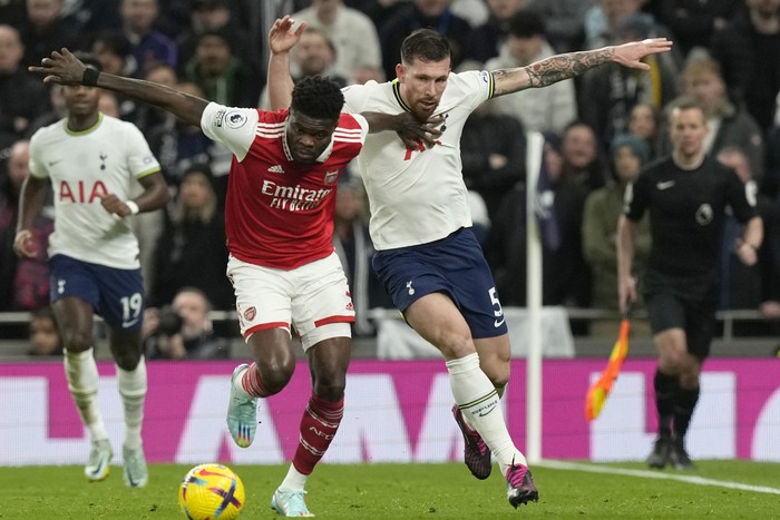 Tottenhams Pierre-Emile Hojbjerg, right, challenges for the ball with Arsenals Thomas Partey during the English Premier League soccer match between Tottenham Hotspur and Arsenal at the Tottenham Hotspur Stadium in London, England, Sunday, Jan. 15, 2023. (AP Photo/Frank Augstein)