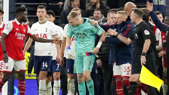 Arsenal goalkeeper Aaron Ramsdale, in green, is ushered away after an incident at the end of the English Premier League soccer match between Tottenham Hotspur and Arsenal at the Tottenham Hotspur Stadium in London, England, Sunday, Jan. 15, 2023. The incident happened when a spectator climbed onto an advertising board and appeared to kick Ramsdale after the teams 2-0 win over Tottenham in the Premier League. (AP Photo/Frank Augstein)