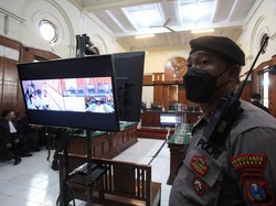 Polisi berjaga di ruang sidang saat sidang perdana tragedi Kanjuruhan di Pengadilan Negeri Surabaya, Jawa Timur.