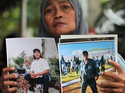 Seorang ibu menunjukkan foto keluarganya yang menjadi korban tragedi Kanjuruhan saat sidang di Pengadilan Negeri Surabaya, Jawa Timur.