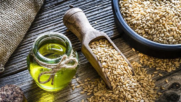 Flax seed oil and brown flax seeds shot on rustic wooden table. Flax seed oil is rich in Omega 3. Predominant colors are brown and yellow. XXXL 42Mp studio photo taken with Sony A7rii and Sony FE 90mm f2.8 macro G OSS lens