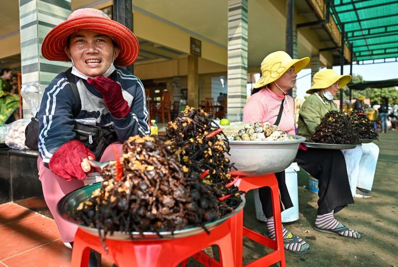 People buy fried tarantulas in the town of Skun in Kampong Cham province on January 15, 2023. (Photo by TANG CHHIN SOTHY / AFP) (Photo by TANG CHHIN SOTHY/AFP via Getty Images)