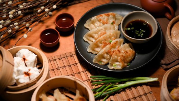 Authentic Chinese cuisine concept with fried dumpling or gyoza, steamed pork buns served with hot tea on dining table.