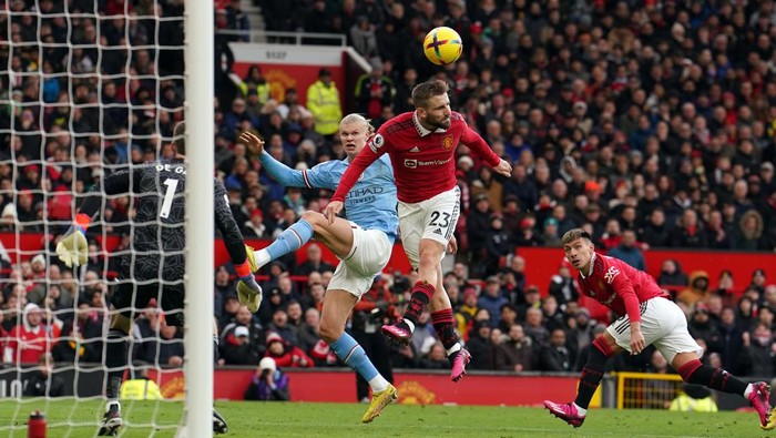 Manchester Uniteds Luke Shaw clears with a defensive header under pressure from Manchester Citys Erling Haaland during the Premier League match at Old Trafford, Manchester. Picture date: Saturday January 14, 2023. (Photo by Martin Rickett/PA Images via Getty Images)