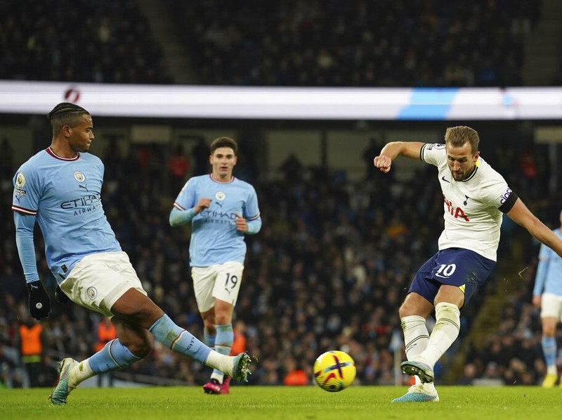 Tottenham's Harry Kane, right, attempts a shot at goal in front of Manchester City's Manuel Akanji during the English Premier League soccer match between Manchester City and Tottenham Hotspur at the Etihad Stadium in Manchester, England, Thursday, Jan. 19, 2023. (AP Photo/Dave Thompson)
