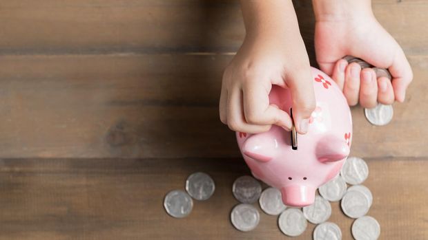 kid put coin to piggy bank on the vintage wood background, a saving money for future education concept and copy space for input text.