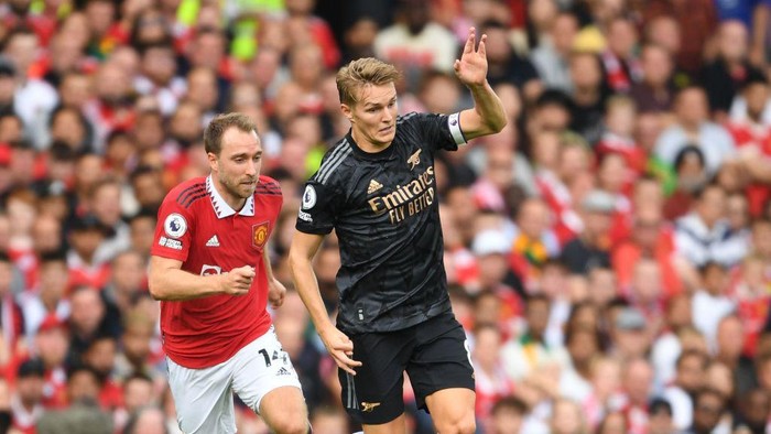 MANCHESTER, ENGLAND - SEPTEMBER 04: Martin Odegaard of Arsenal breaks past Christian Eriksen of Man United during the Premier League match between Manchester United and Arsenal FC at Old Trafford on September 04, 2022 in Manchester, England. (Photo by Stuart MacFarlane/Arsenal FC via Getty Images)