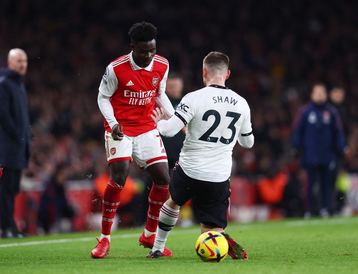 Soccer Football - Premier League - Arsenal v Manchester United - Emirates Stadium, London, Britain - January 22, 2023 Arsenals Bukayo Saka in action with Manchester Uniteds Luke Shaw REUTERS/David Klein EDITORIAL USE ONLY. No use with unauthorized audio, video, data, fixture lists, club/league logos or live services. Online in-match use limited to 75 images, no video emulation. No use in betting, games or single club /league/player publications.  Please contact your account representative for further details.