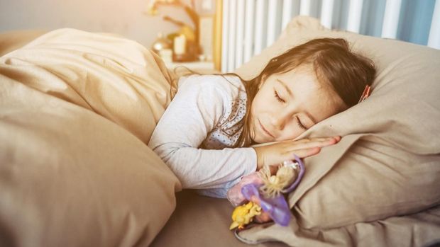 little girl is sleeping on the bed in the bedroom