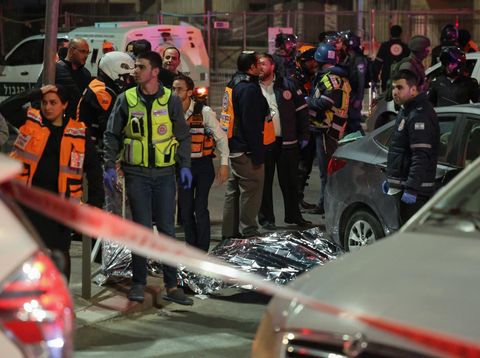 Israeli emergency service personnel and security forces stand near a covered body at the site of a reported attack in a settler neighbourhood of Israeli-annexed east Jerusalem, on January 27, 2023. (Photo by AHMAD GHARABLI / AFP)