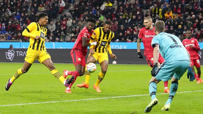 Dortmunds Jude Bellingham, left scores his sides second goal passing Leverkusens goalkeeper Lukas Hradecky, in blue, during the German Bundesliga soccer match between Bayer Leverkusen and Borussia Dortmund at the BayArena in Leverkusen, Germany, Germany, Sunday, Jan. 29, 2023. (AP Photo/Martin Meissner)