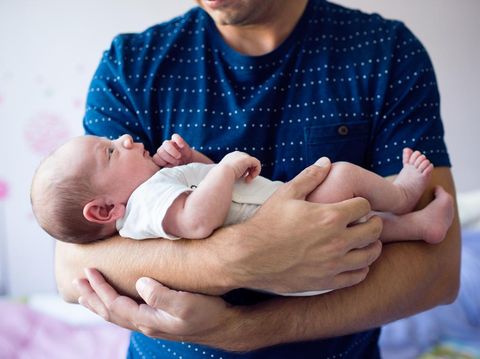 A proud father holding his newborn son wrapped in a blanket in the hospital