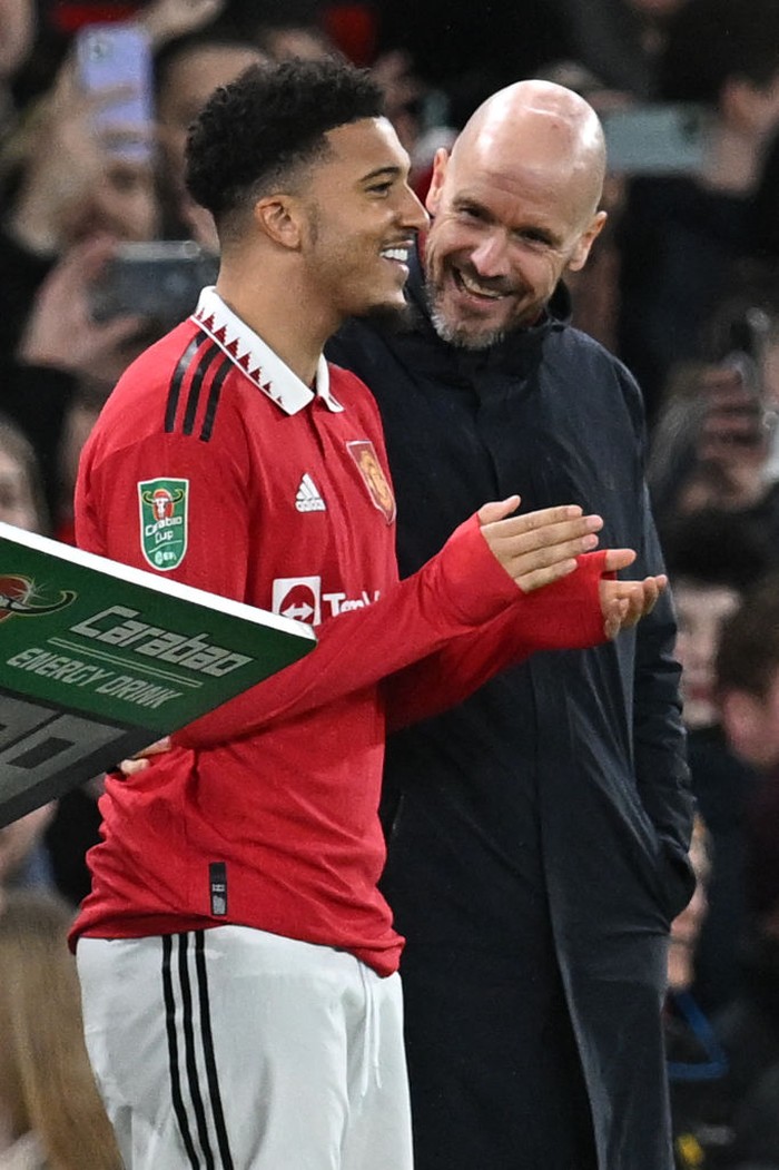 Manchester United's Dutch manager Erik ten Hag (R) talks with Manchester United's English striker Jadon Sancho as Sancho waits to be substituted on during the English League Cup semi-final second-leg  football match between Manchester United and Nottingham Forest at Old Trafford in Manchester, north west England, on February 1, 2023. - RESTRICTED TO EDITORIAL USE. No use with unauthorized audio, video, data, fixture lists, club/league logos or 'live' services. Online in-match use limited to 120 images. An additional 40 images may be used in extra time. No video emulation. Social media in-match use limited to 120 images. An additional 40 images may be used in extra time. No use in betting publications, games or single club/league/player publications. (Photo by Paul ELLIS / AFP) / RESTRICTED TO EDITORIAL USE. No use with unauthorized audio, video, data, fixture lists, club/league logos or 'live' services. Online in-match use limited to 120 images. An additional 40 images may be used in extra time. No video emulation. Social media in-match use limited to 120 images. An additional 40 images may be used in extra time. No use in betting publications, games or single club/league/player publications. / RESTRICTED TO EDITORIAL USE. No use with unauthorized audio, video, data, fixture lists, club/league logos or 'live' services. Online in-match use limited to 120 images. An additional 40 images may be used in extra time. No video emulation. Social media in-match use limited to 120 images. An additional 40 images may be used in extra time. No use in betting publications, games or single club/league/player publications. (Photo by PAUL ELLIS/AFP via Getty Images)