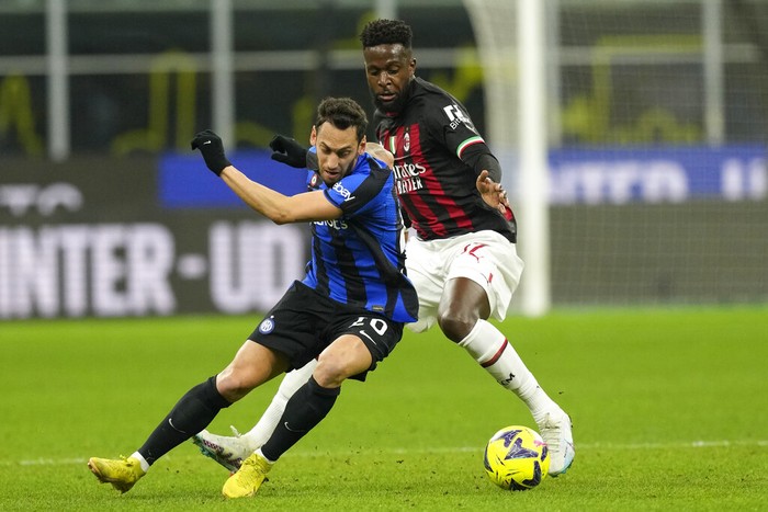 Inter Milan's Hakan Calhanoglu, left, duels for the ball with AC Milan's Divock Origi during the Serie A soccer match between Inter Milan and AC Milan at the San Siro Stadium, in Milan, Italy, Sunday, Feb. 5, 2023. (AP Photo/Antonio Calanni)