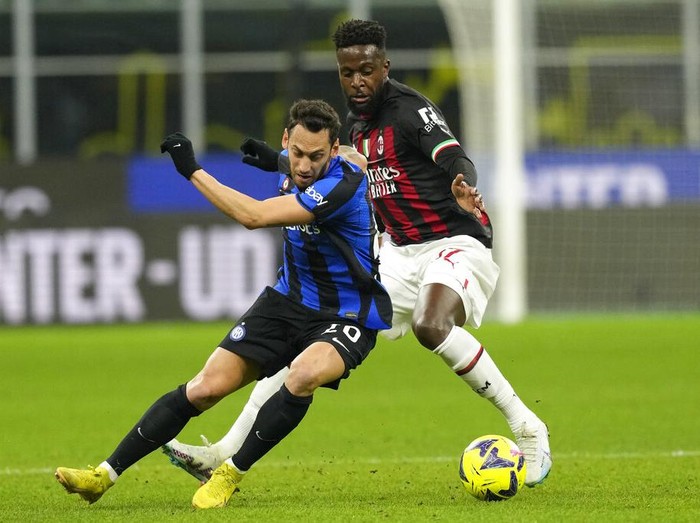 Inter Milans Hakan Calhanoglu, left, duels for the ball with AC Milans Divock Origi during the Serie A soccer match between Inter Milan and AC Milan at the San Siro Stadium, in Milan, Italy, Sunday, Feb. 5, 2023. (AP Photo/Antonio Calanni)